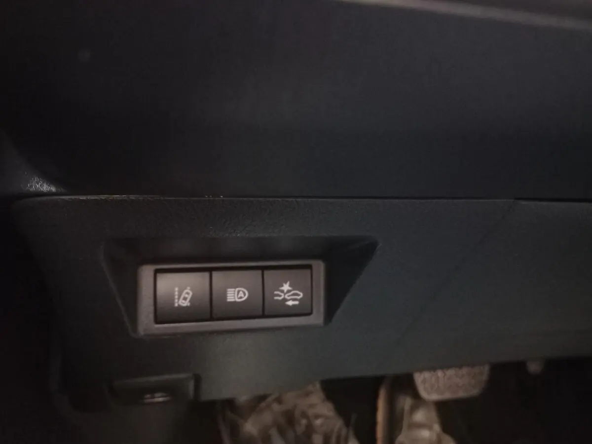 Gros plan sur les commandes d'assistance à la conduite sous le tableau de bord d'une Toyota Yaris blanche hybride 2019.