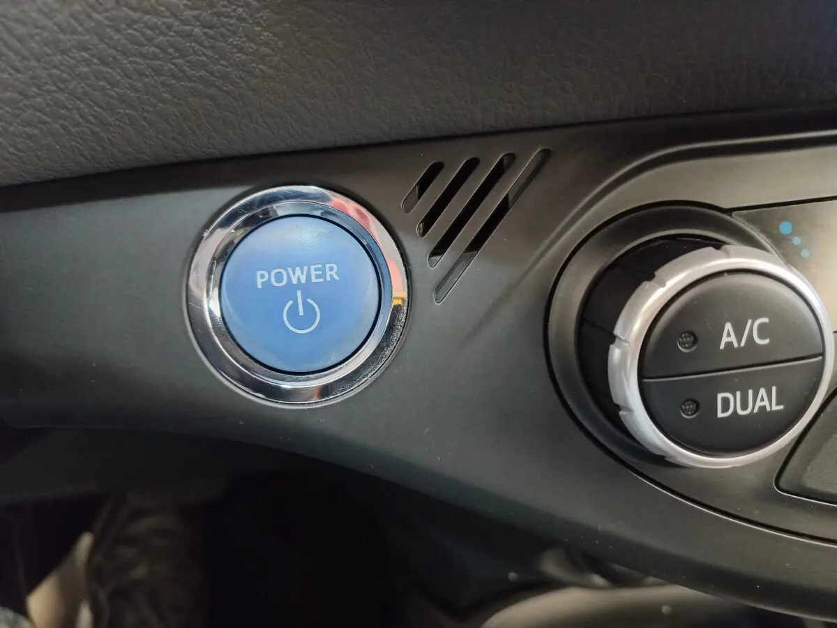 Gros plan sur le bouton bleu Power et la commande de climatisation dual de la Toyota Yaris hybride blanche 2019.