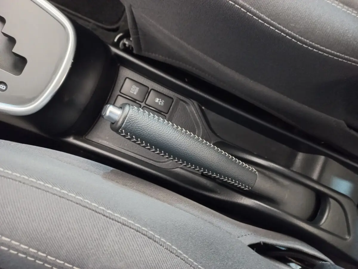 Gros plan sur le frein à main en cuir noir avec surpiqûres blanches dans l'habitacle de la Toyota Yaris hybride 2019.