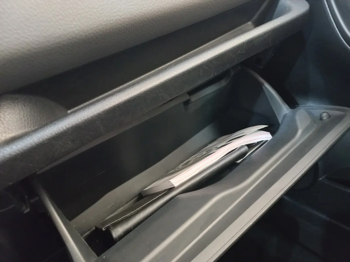 Gros plan sur la boîte à gants ouverte de la Toyota Yaris 1.5 VVT-I Hybride, montrant des documents à l'intérieur.