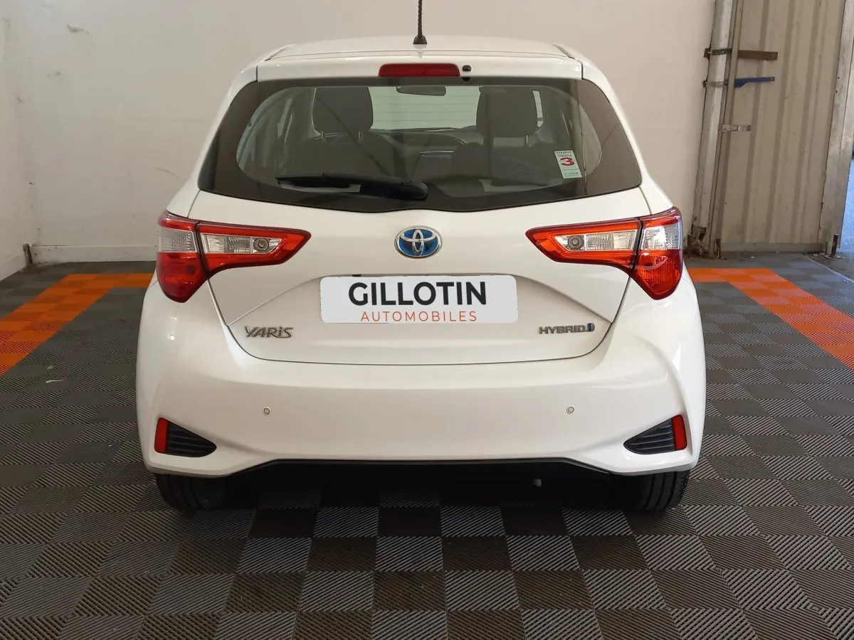 Vue arrière d'une Toyota Yaris blanche hybride 2019 avec feux arrière distinctifs et logo Toyota visible.