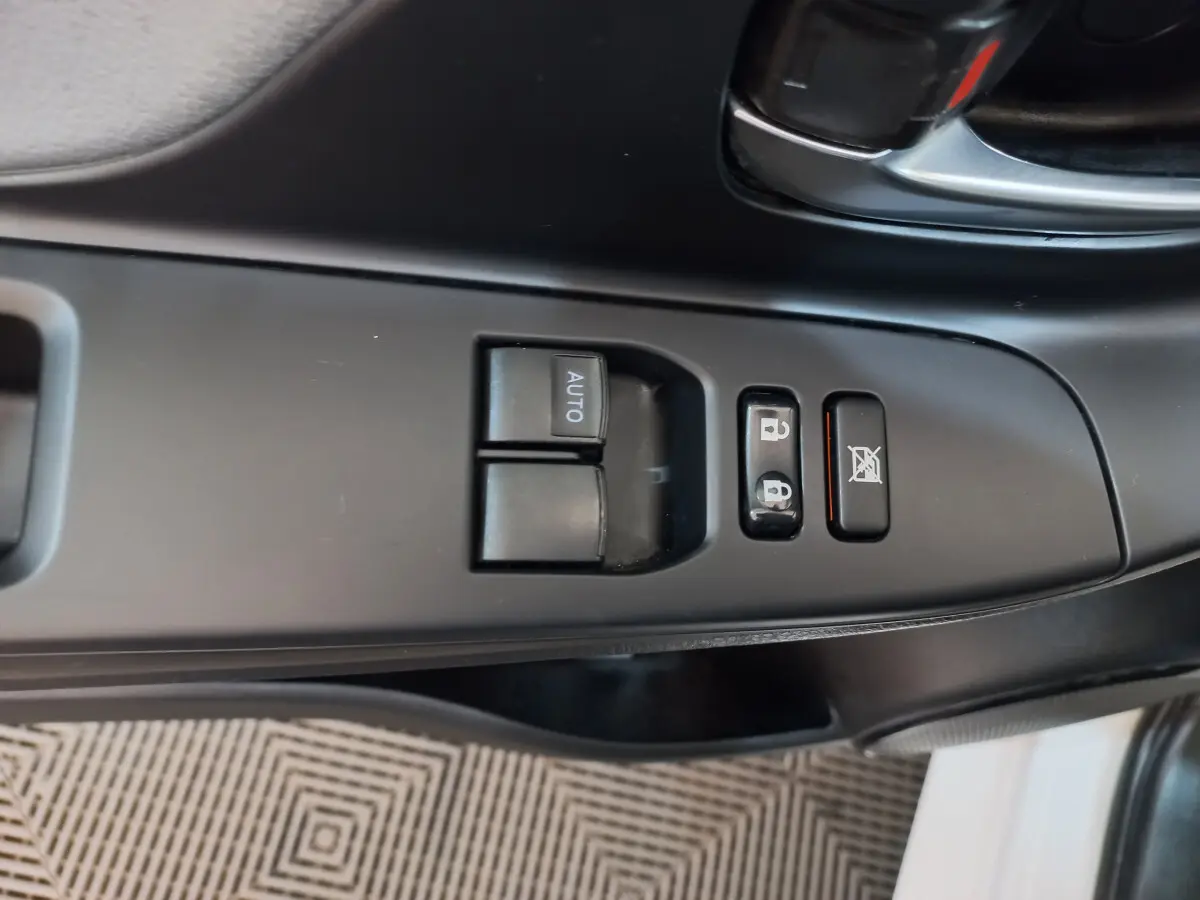 Gros plan sur les commandes de lève-vitres et verrouillage côté conducteur d'une Toyota Yaris blanche 2019.