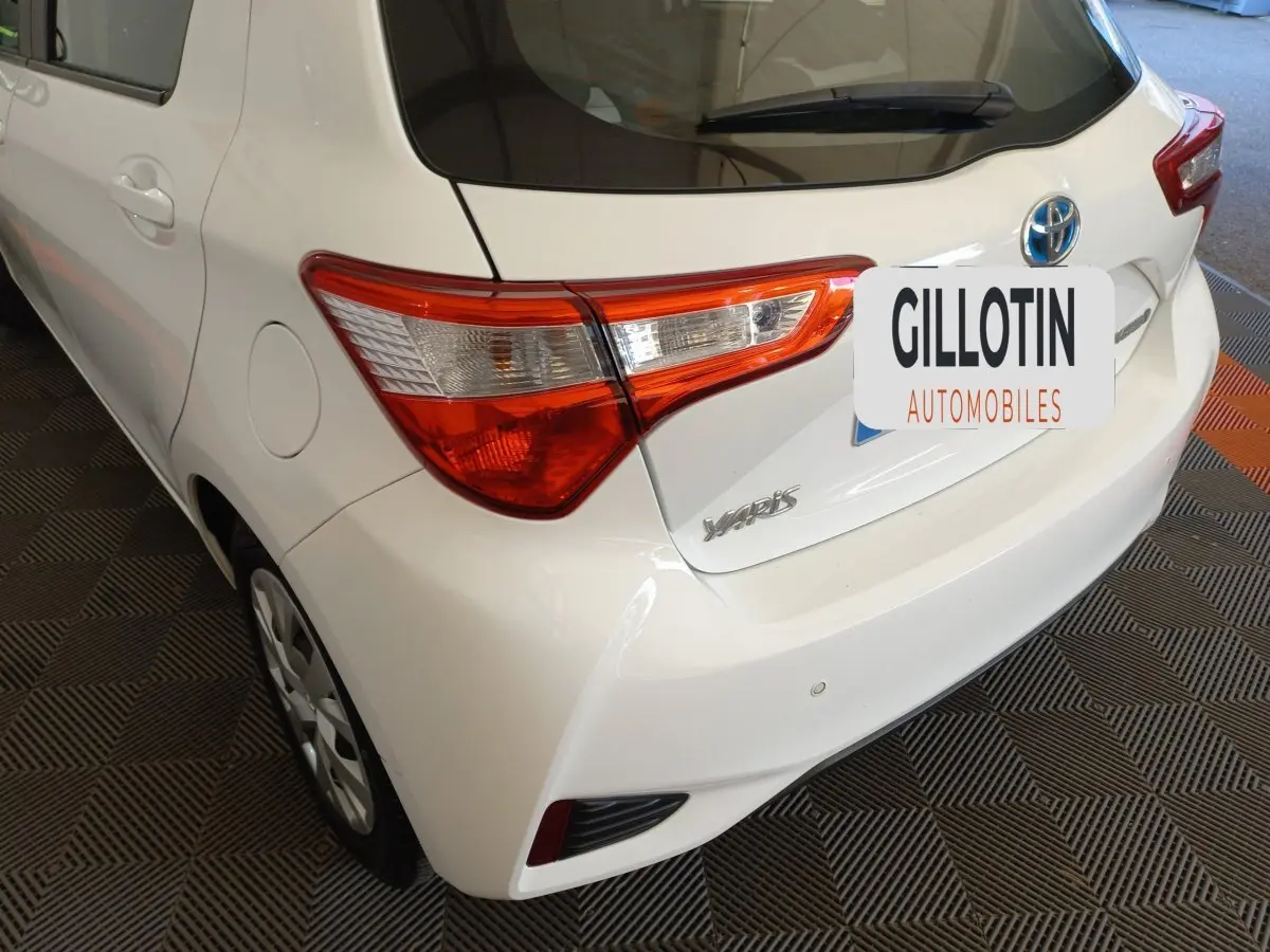 Vue 3/4 arrière droite d'une Toyota Yaris blanche, mettant en valeur les feux arrière et le logo Toyota sur le hayon.