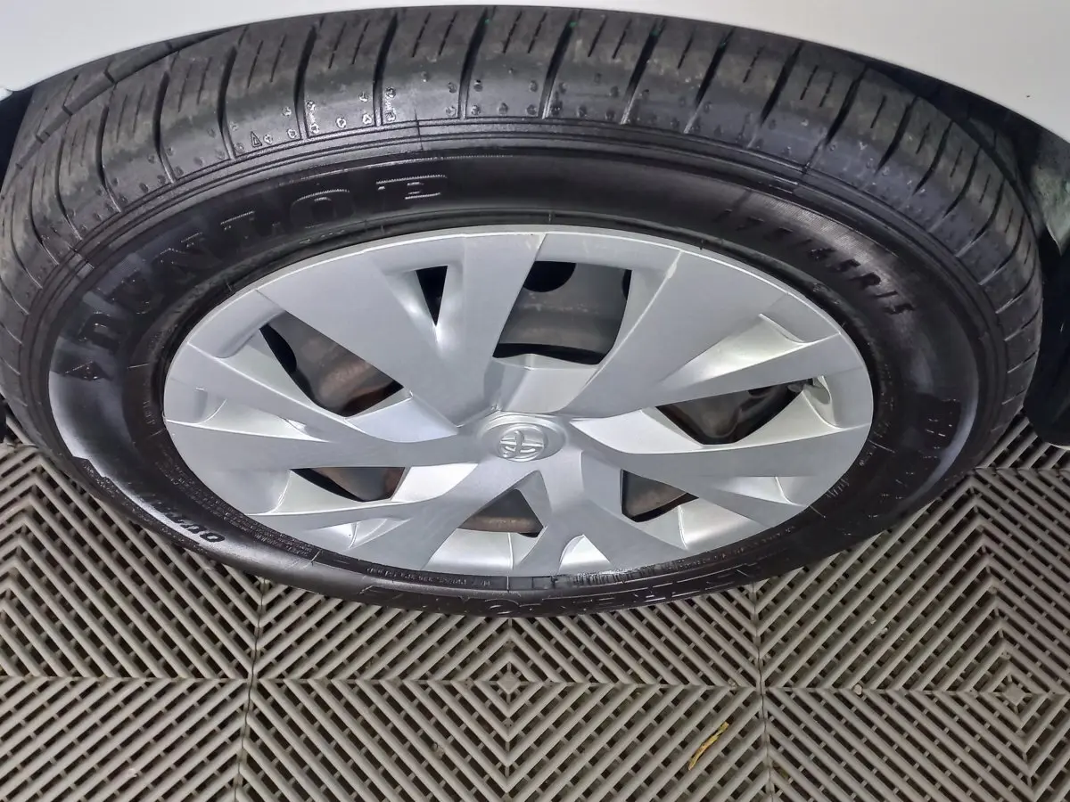 Gros plan sur la roue avant droite de la Toyota Yaris blanche avec jante en alliage et pneu Dunlop.