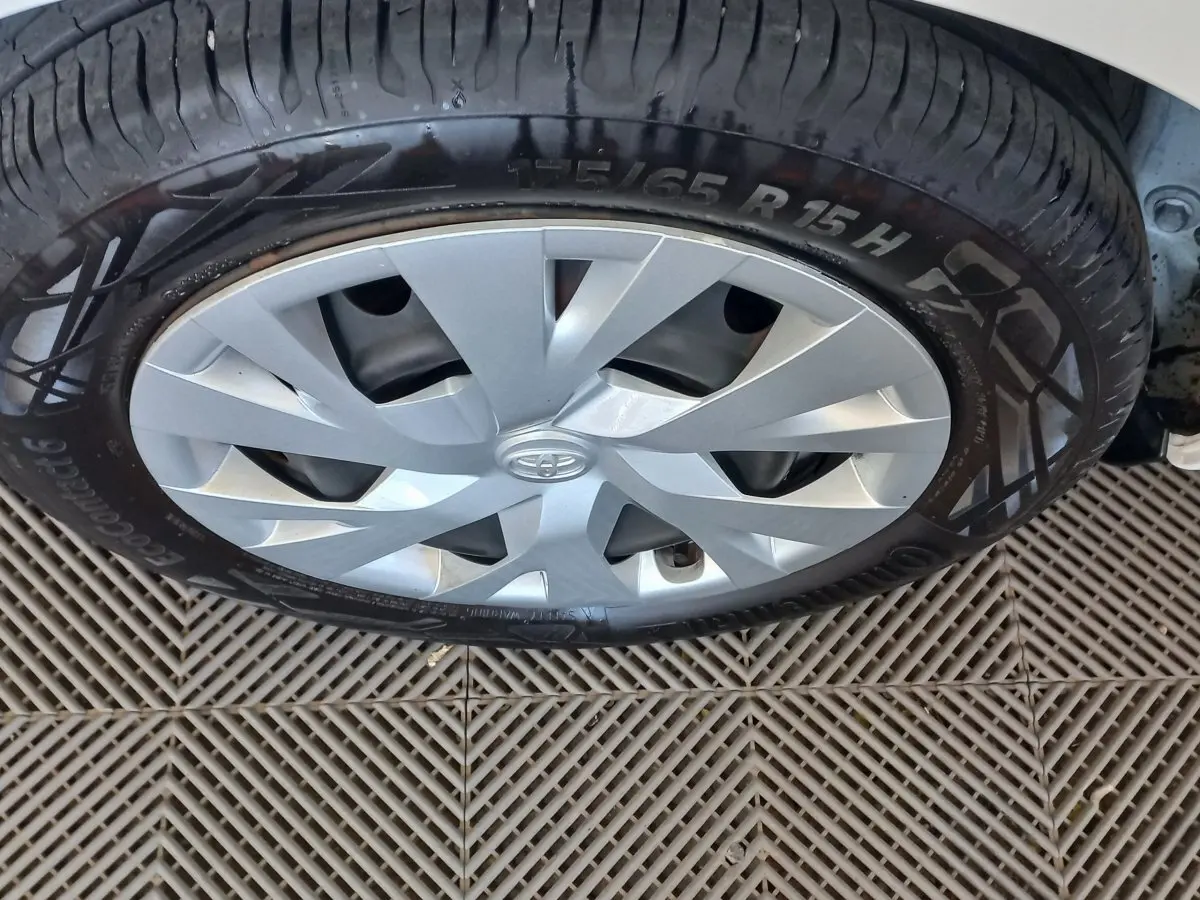 Gros plan sur la roue avant droite d'une Toyota Yaris blanche, mettant en valeur la jante argentée et le pneu Continental.