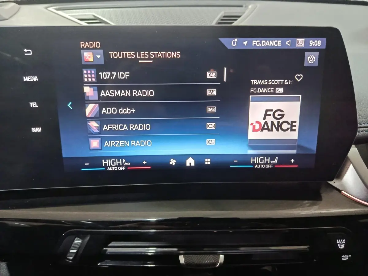 Écran tactile central affichant les stations radio dans l’habitacle du BMW X1 blanc, vue de face.