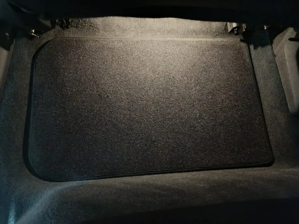 Vue rapprochée du coffre intérieur avec tapis de sol noir du BMW X1 xDrive25e M Sport blanc 2024.
