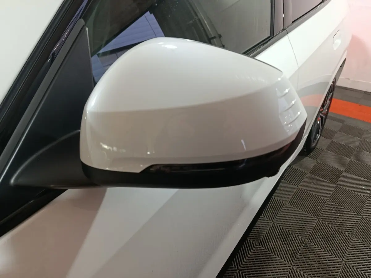 Gros plan sur le rétroviseur droit blanc du BMW X1 xDrive25e M Sport 2024, avec clignotant intégré noir.