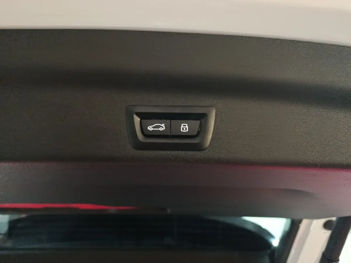 Boutons d'ouverture et de verrouillage du coffre sur la partie intérieure du hayon d'un BMW X1 blanc hybride rechargeable.