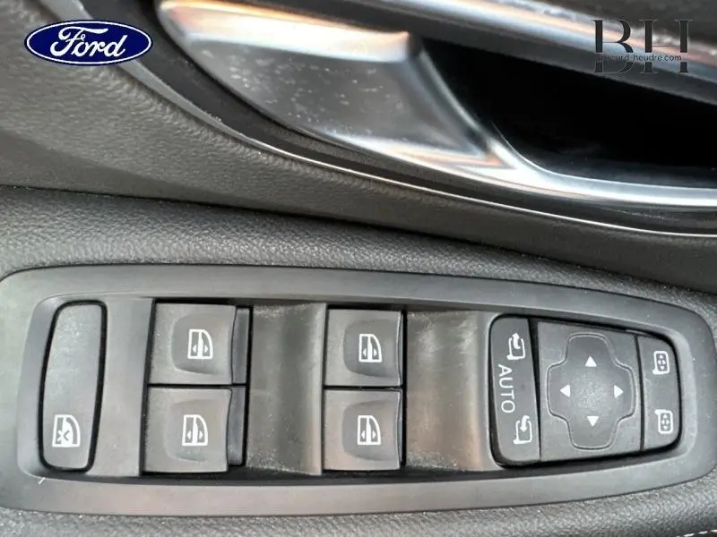 Gros plan sur les commandes des vitres électriques et rétroviseurs côté conducteur d’un Renault Grand Scenic noir étoilé.