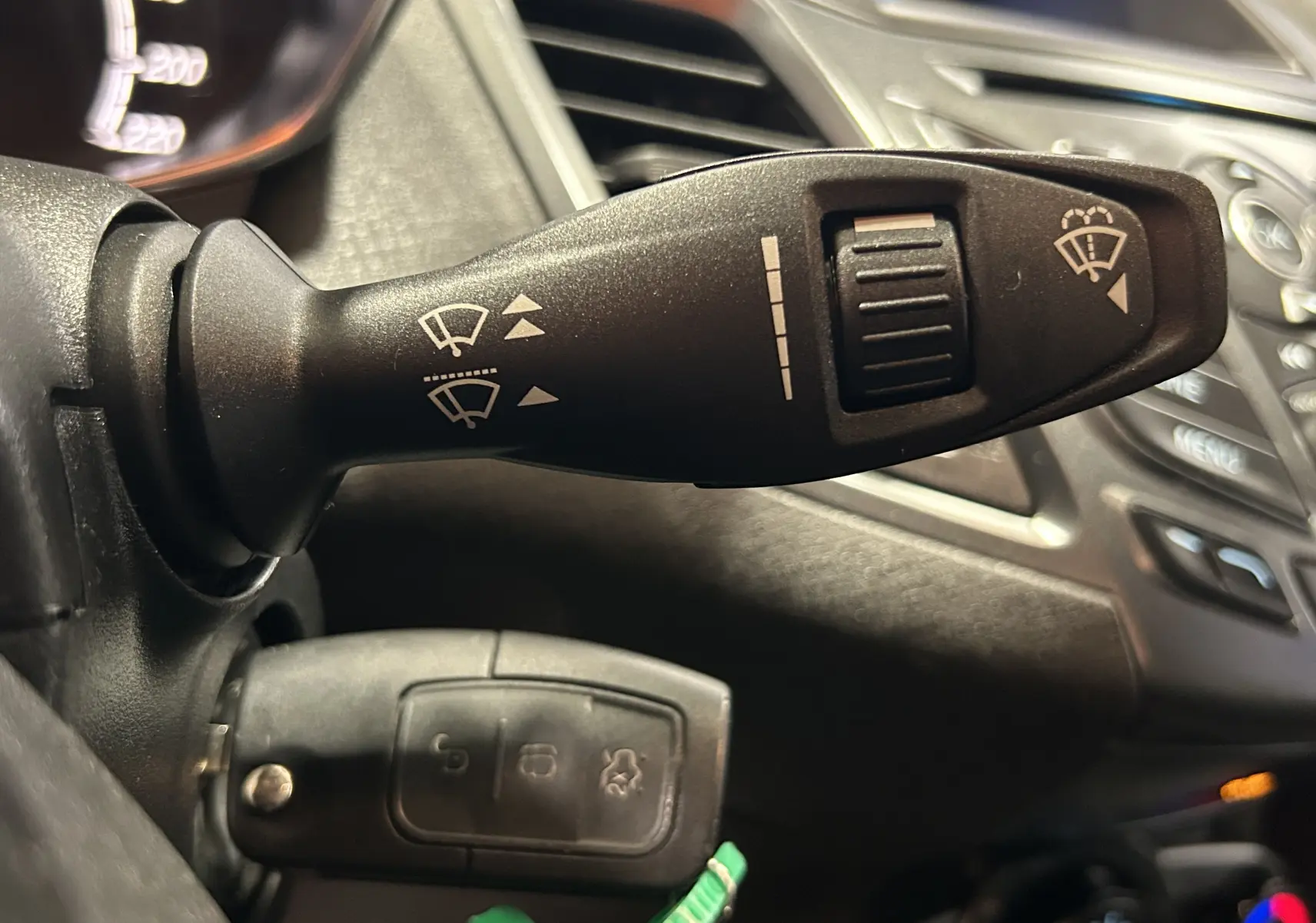 Gros plan sur la manette de commande des essuie-glaces dans l’habitacle d’une Ford Fiesta blanche de 2015.