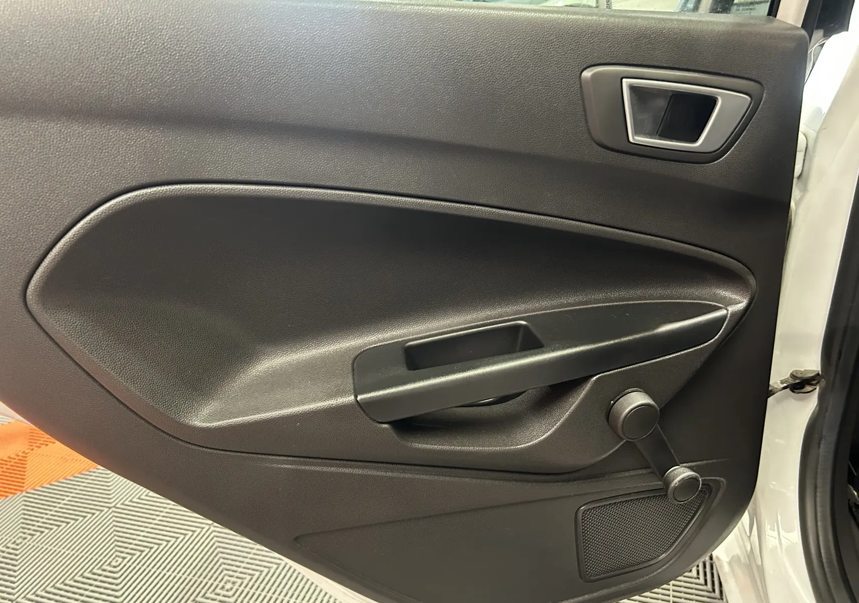 Vue rapprochée de la porte avant gauche noire avec manivelle de la Ford Fiesta blanche de 2015.