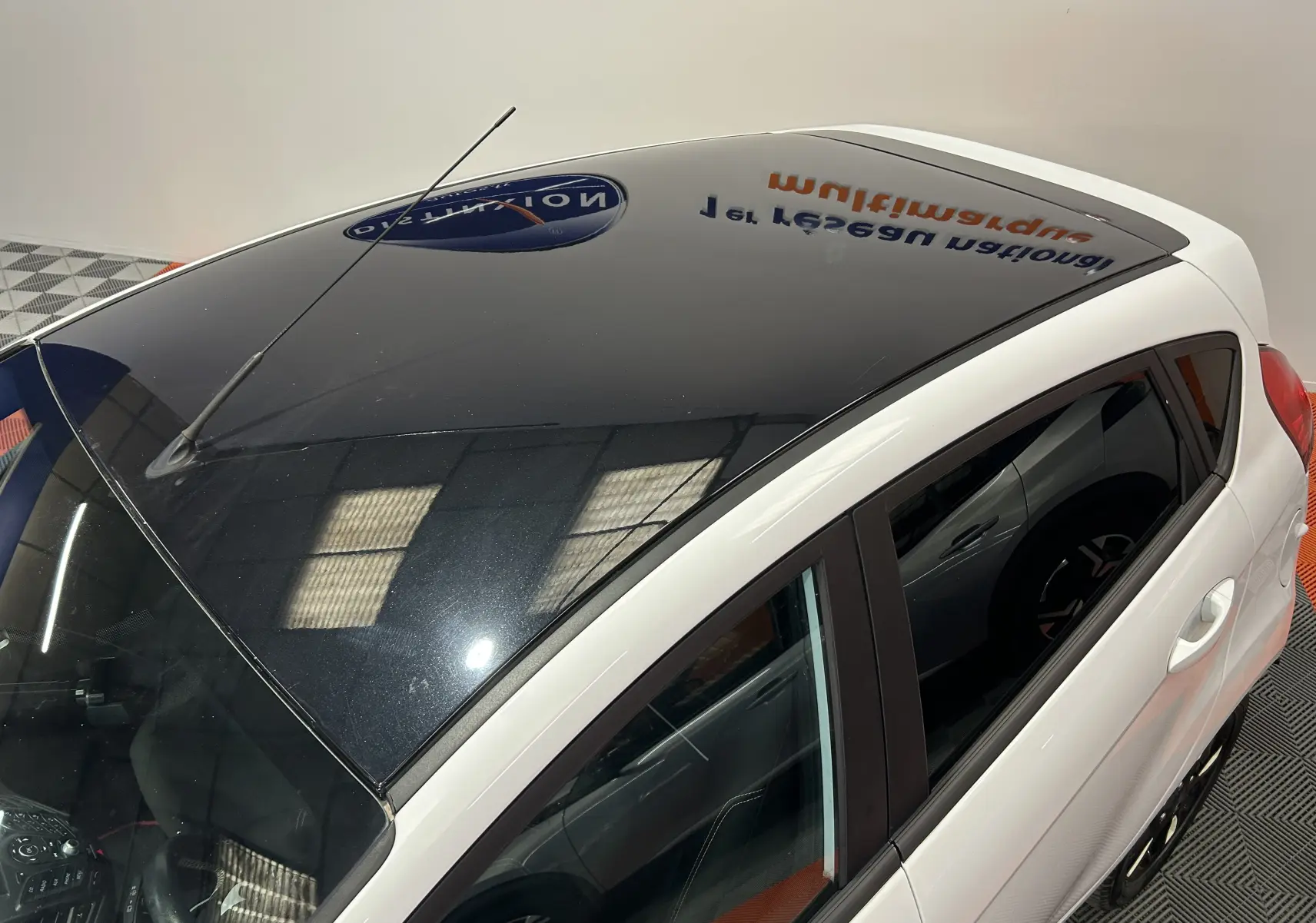 Vue plongeante sur le côté gauche d'une Ford Fiesta blanche avec toit noir brillant et vitres teintées.