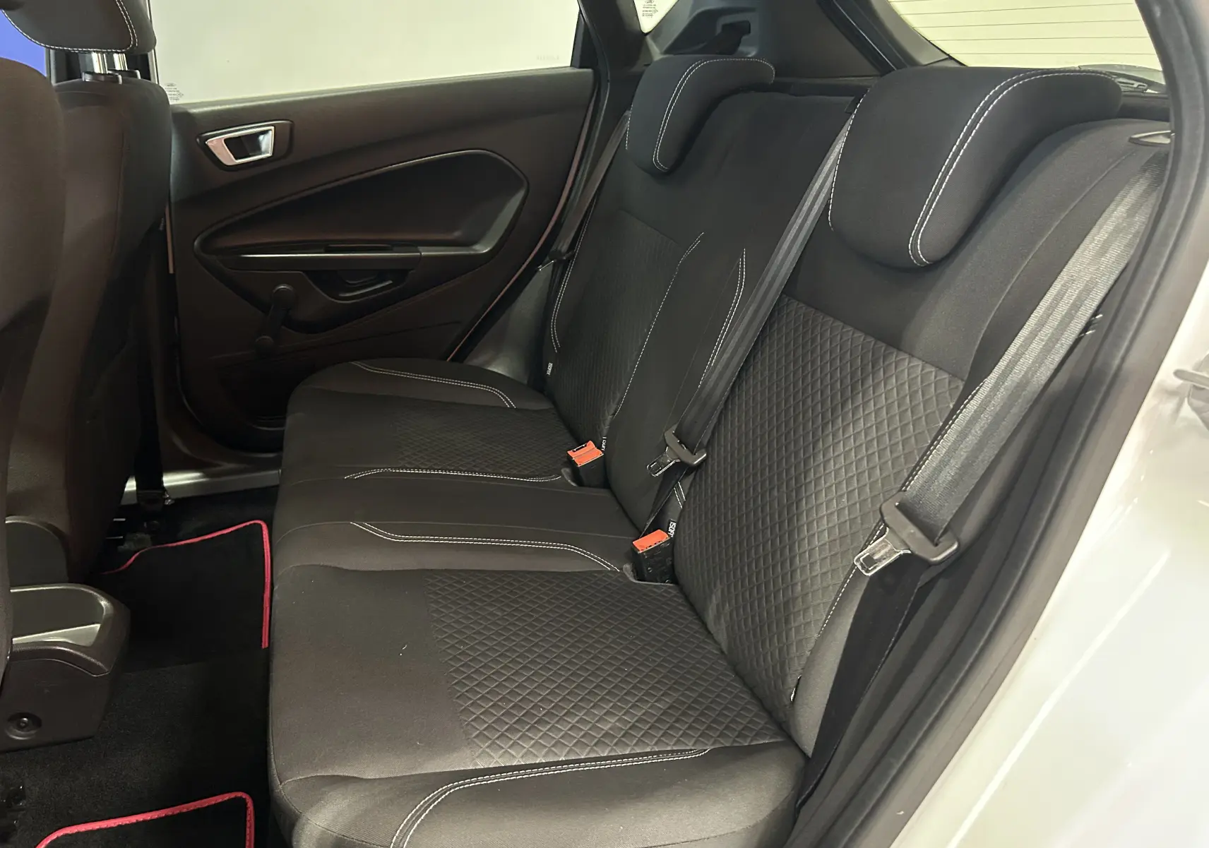 Vue intérieure côté droit des sièges arrière noirs avec surpiqûres blanches de la Ford Fiesta blanche 5 portes de 2015.
