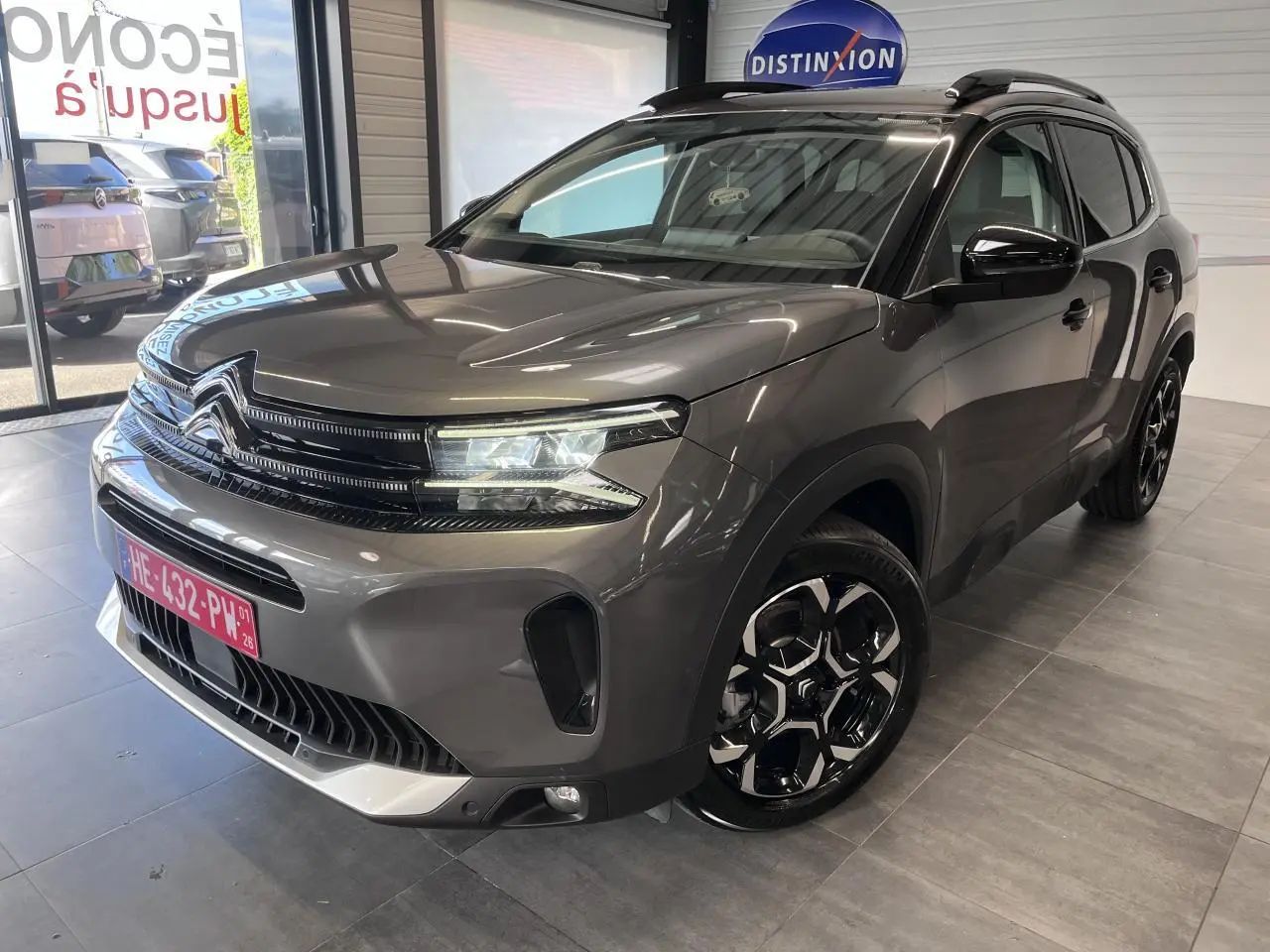 Vue 3/4 avant droite du Citroën C5 Aircross gris platinium avec jantes alliage bi-ton et barres de toit noires.
