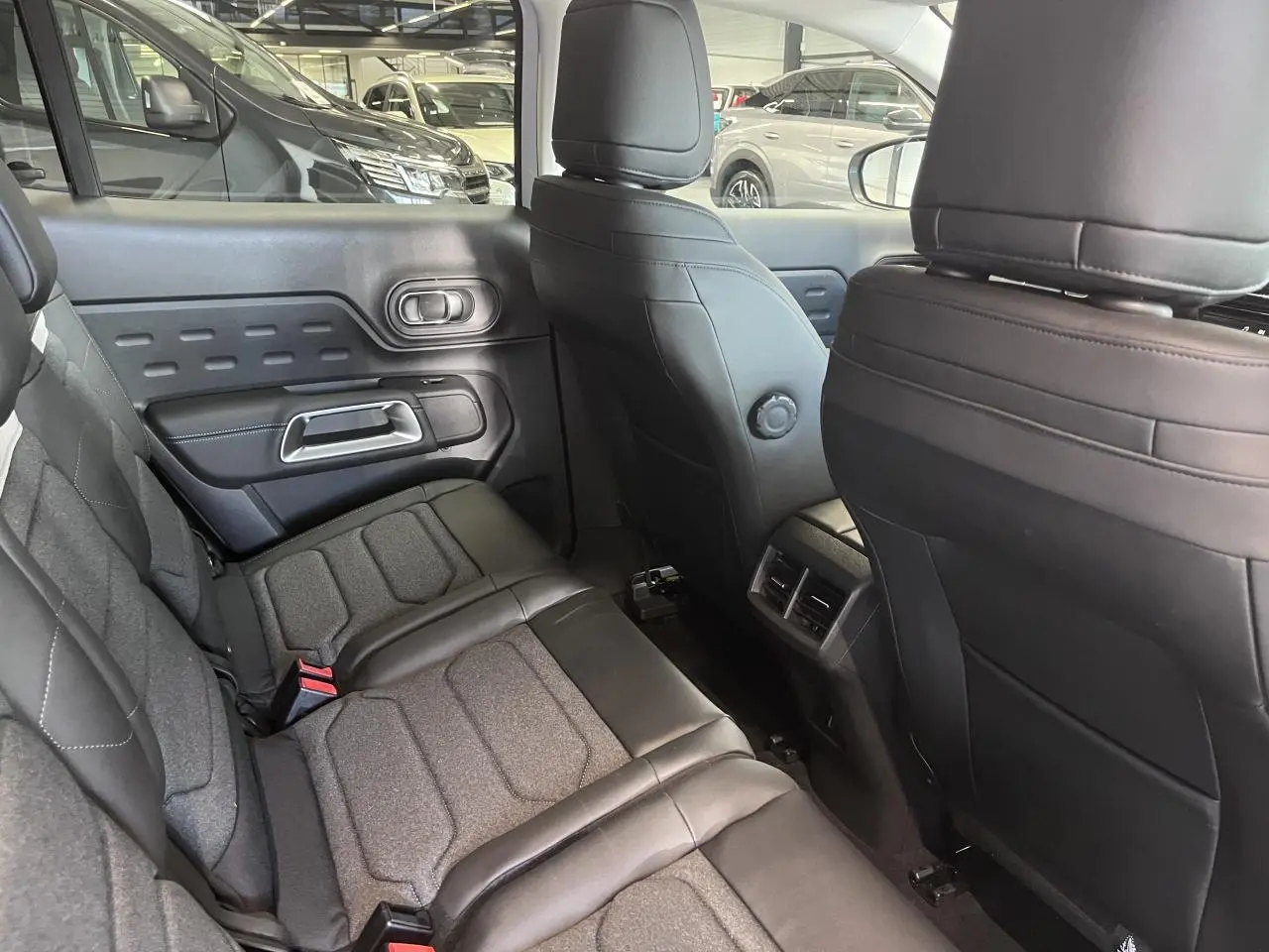 Vue intérieure arrière côté gauche du Citroën C5 Aircross 2025, sièges tissu et cuir noir avec surpiqûres.