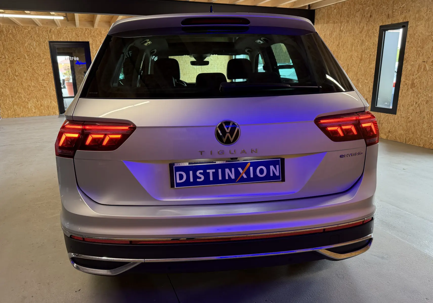 Vue arrière d'un Volkswagen Tiguan gris clair 1.4 e-Hybrid avec feux LED allumés dans un garage.