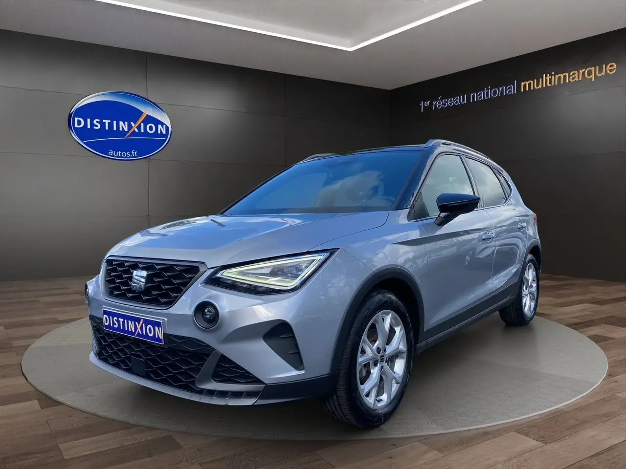 SEAT Arona gris silver avec toit noir en 3/4 avant droit, jantes alu 17 pouces et feux LED allumés.