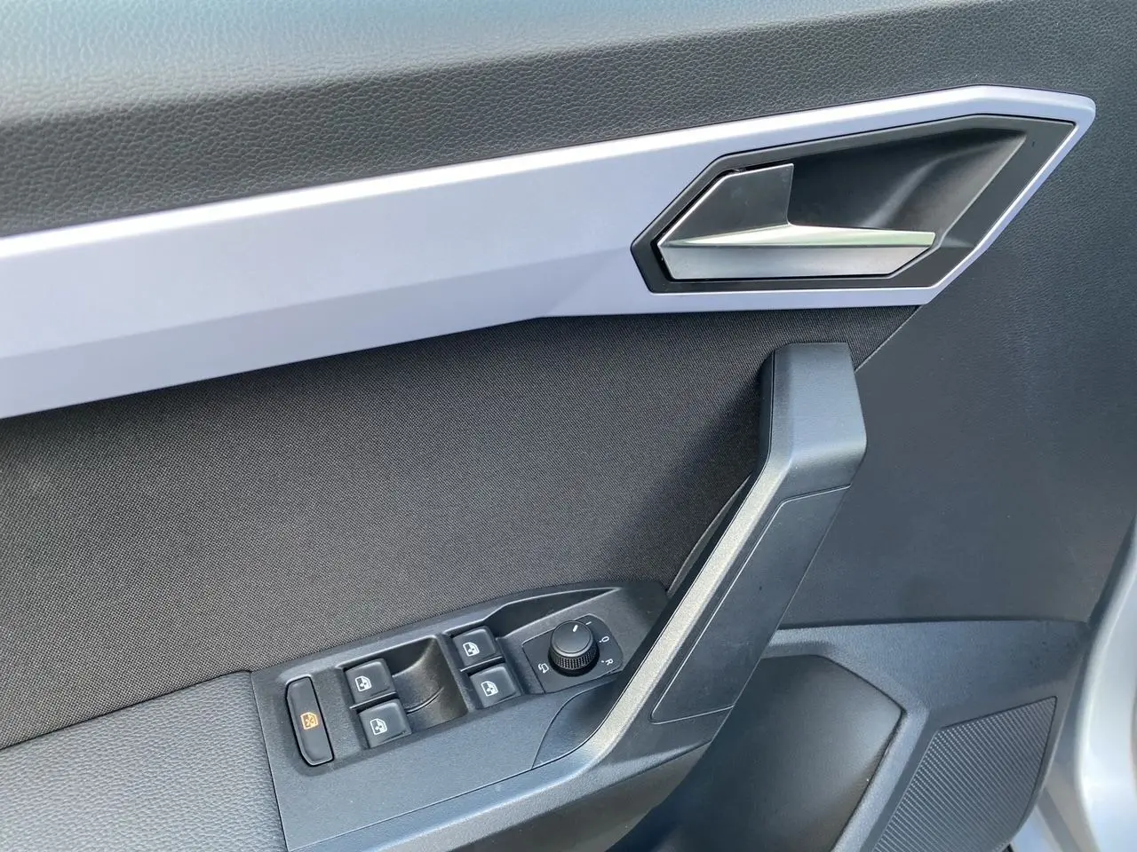 Gros plan sur la porte côté conducteur du SEAT Arona gris silver avec garniture noire et commandes électriques.