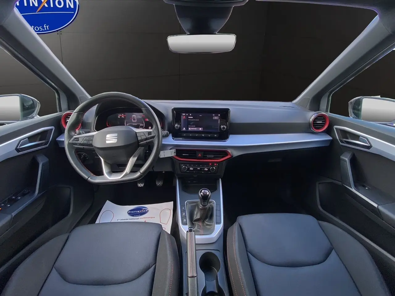 Intérieur avant du SEAT Arona 2024 avec volant multifonction, écran tactile central et sellerie noire en tissu.
