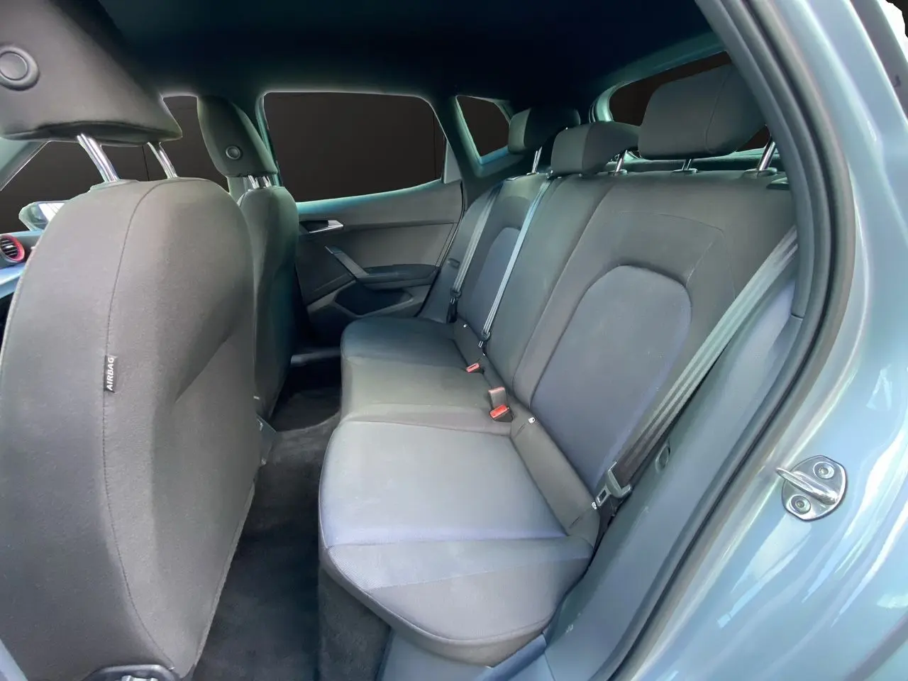 Vue intérieure côté droit sur les sièges arrière noirs en tissu du SEAT Arona 2024 gris silver avec porte ouverte.