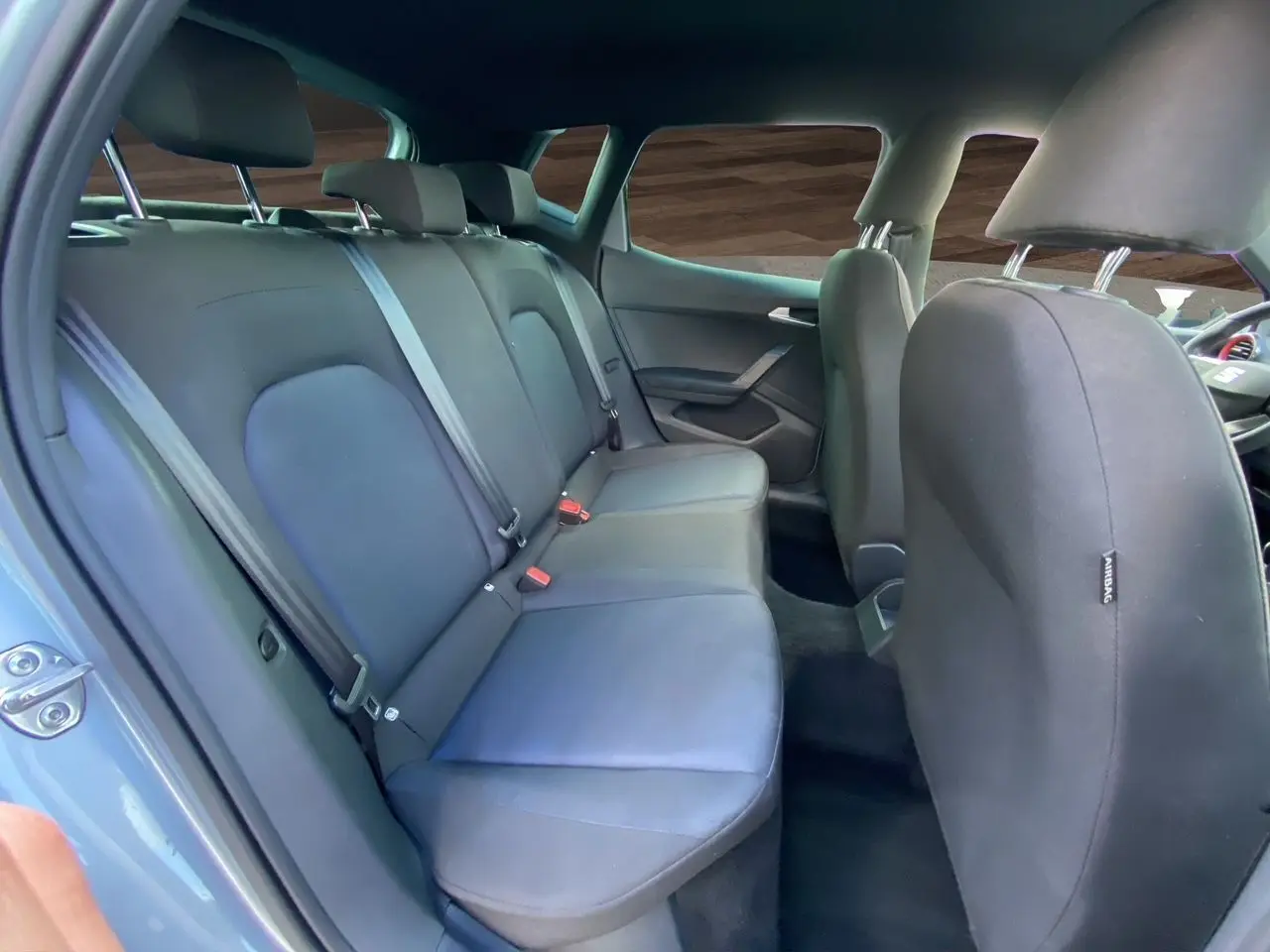 Vue intérieure arrière de la SEAT Arona 2024 avec sièges tissu noir et ceintures de sécurité visibles.