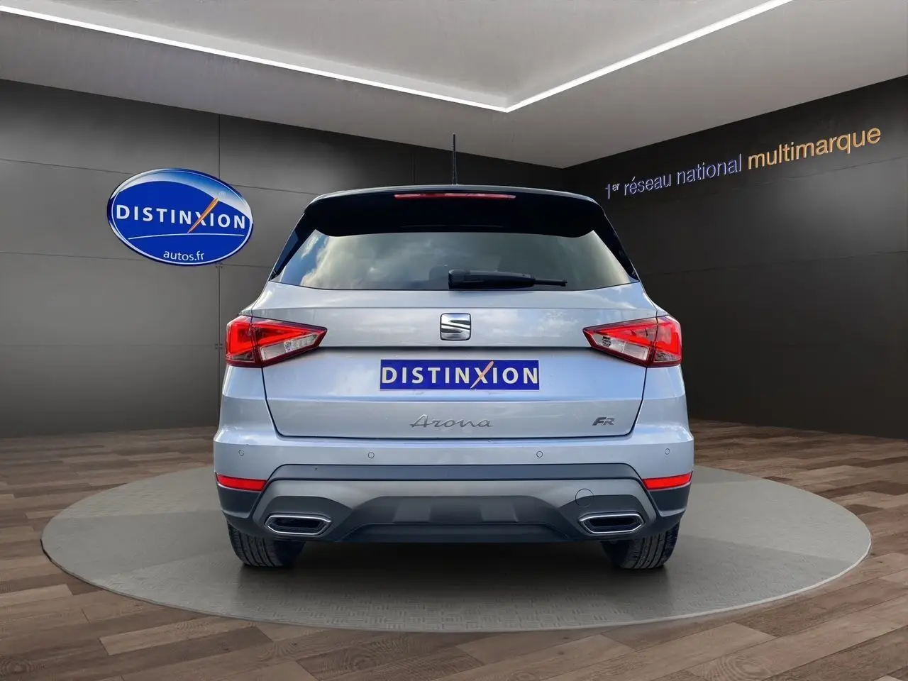 Vue arrière d'une SEAT Arona gris silver avec toit noir et double sortie d'échappement intégrée, en intérieur showroom.