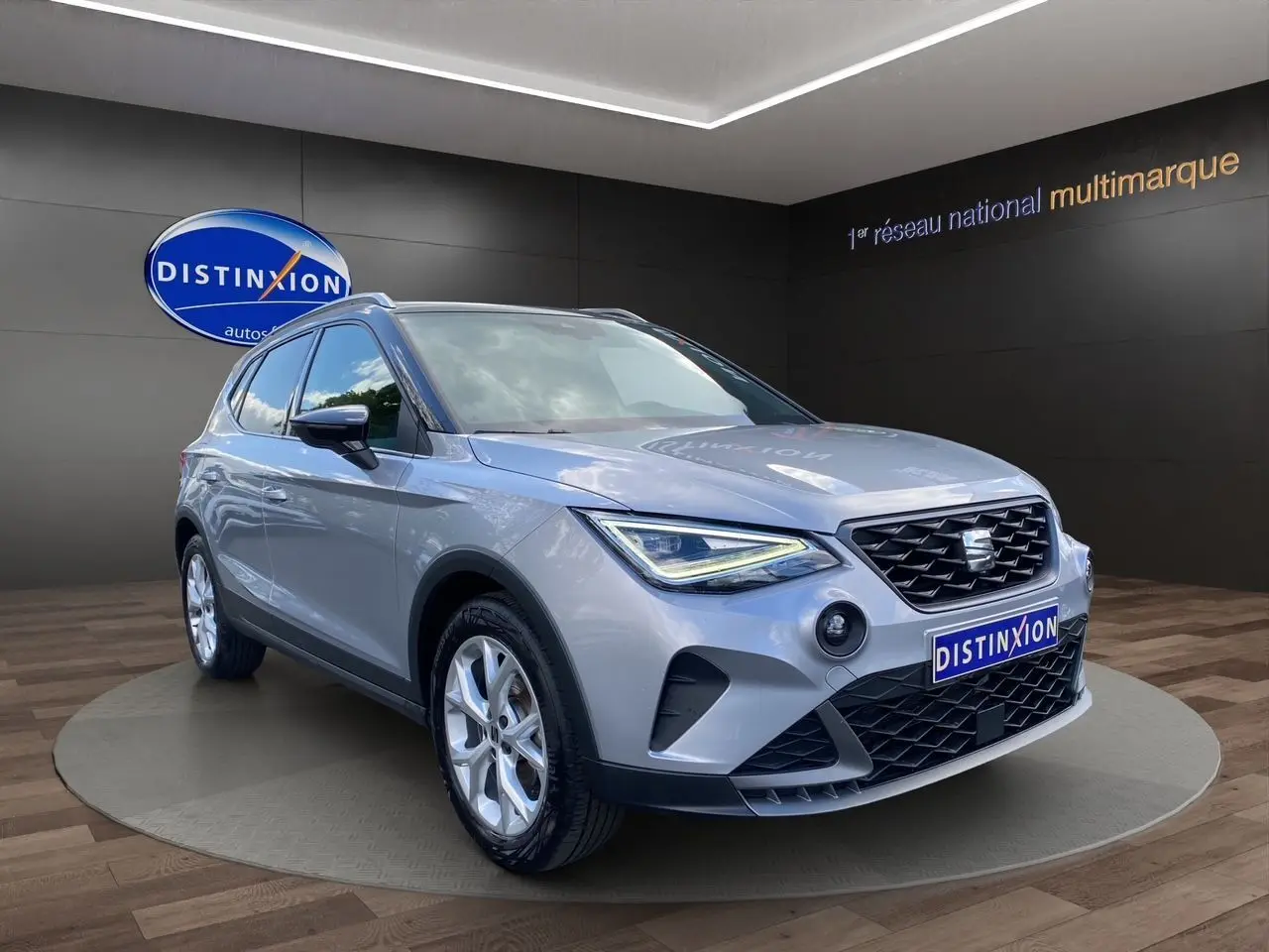 SEAT Arona gris silver avec toit noir, vue 3/4 avant droit, jantes alu 17 pouces et feux LED allumés.