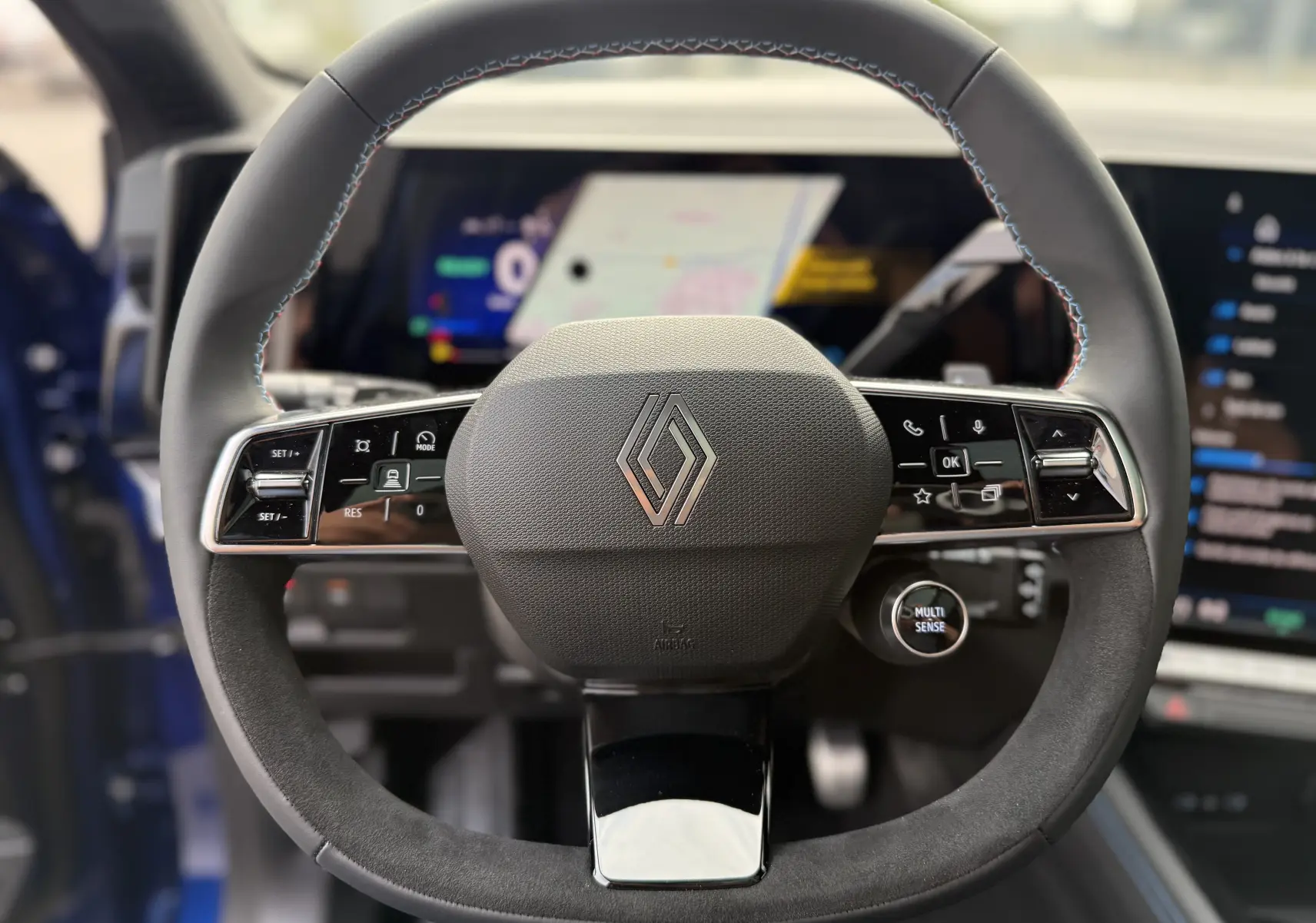 Gros plan sur le volant cuir du Renault Austral 2025, avec commandes intégrées et logo Renault au centre.