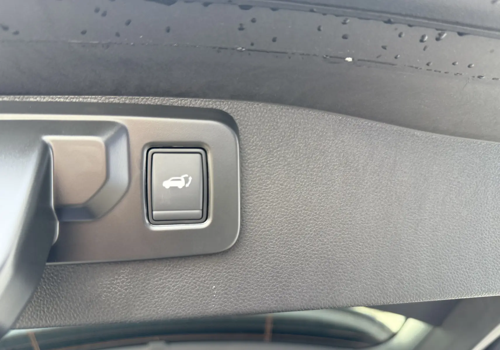 Bouton d'ouverture électrique du coffre sur le hayon intérieur d'un Renault Austral bleu Iron toit noir 2025.