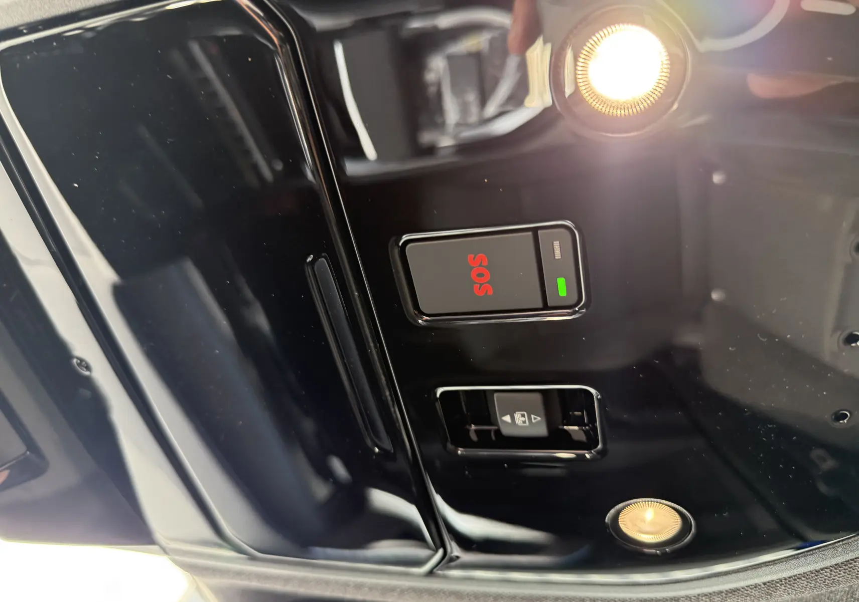 Détail du plafonnier noir brillant du Renault Austral 2025 avec bouton SOS rouge et éclairage intérieur allumé.