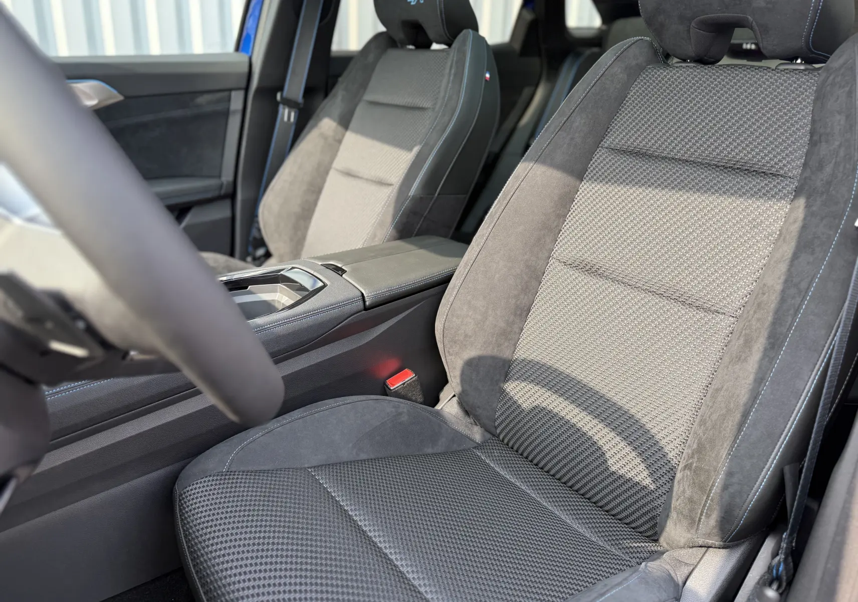 Gros plan sur les sièges avant en tissu et alcantara gris avec surpiqûres bleues du Renault Austral 2025 finition Esprit Alpine.
