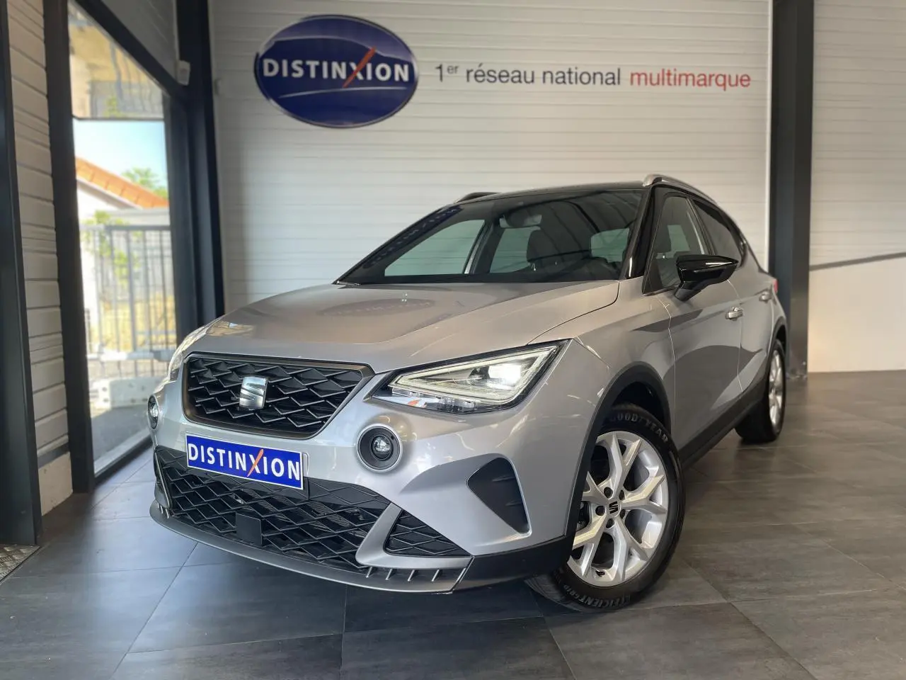 SEAT Arona 2024 gris GRS en 3/4 avant droit, avec calandre noire et jantes alliage 16 pouces visibles.