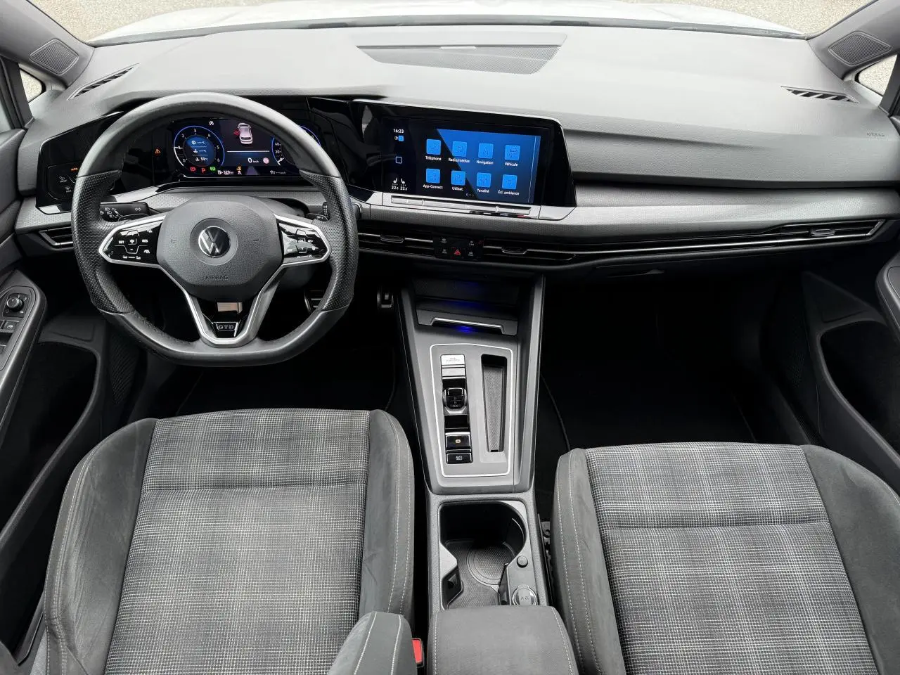 Vue intérieure frontale du poste de conduite de la Volkswagen Golf VIII GTD avec volant sport cuir et écran tactile central.