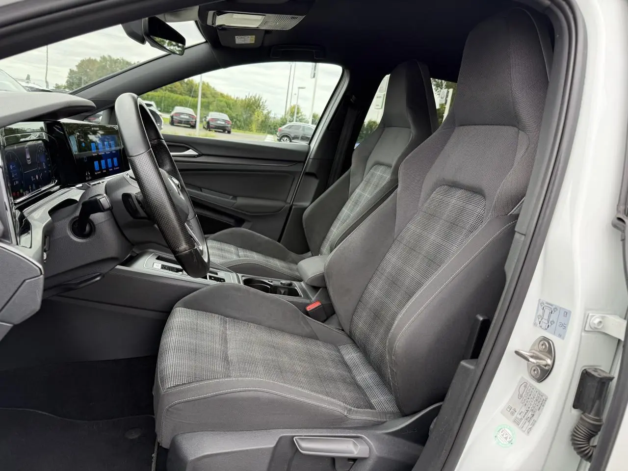 Intérieur côté conducteur d'une Volkswagen Golf GTD blanche 2022, sièges sport gris et tableau de bord numérique.