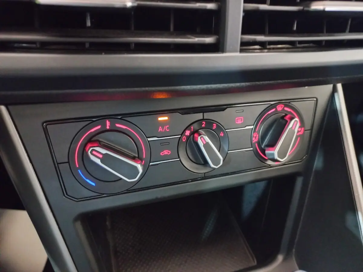 Gros plan sur les commandes de climatisation avec éclairage rouge à l'intérieur d'une Volkswagen Polo noire de 2020.