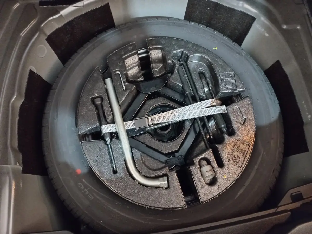 Gros plan sur la roue de secours et les outils de bord dans le coffre d'une Volkswagen Polo noire 2020.