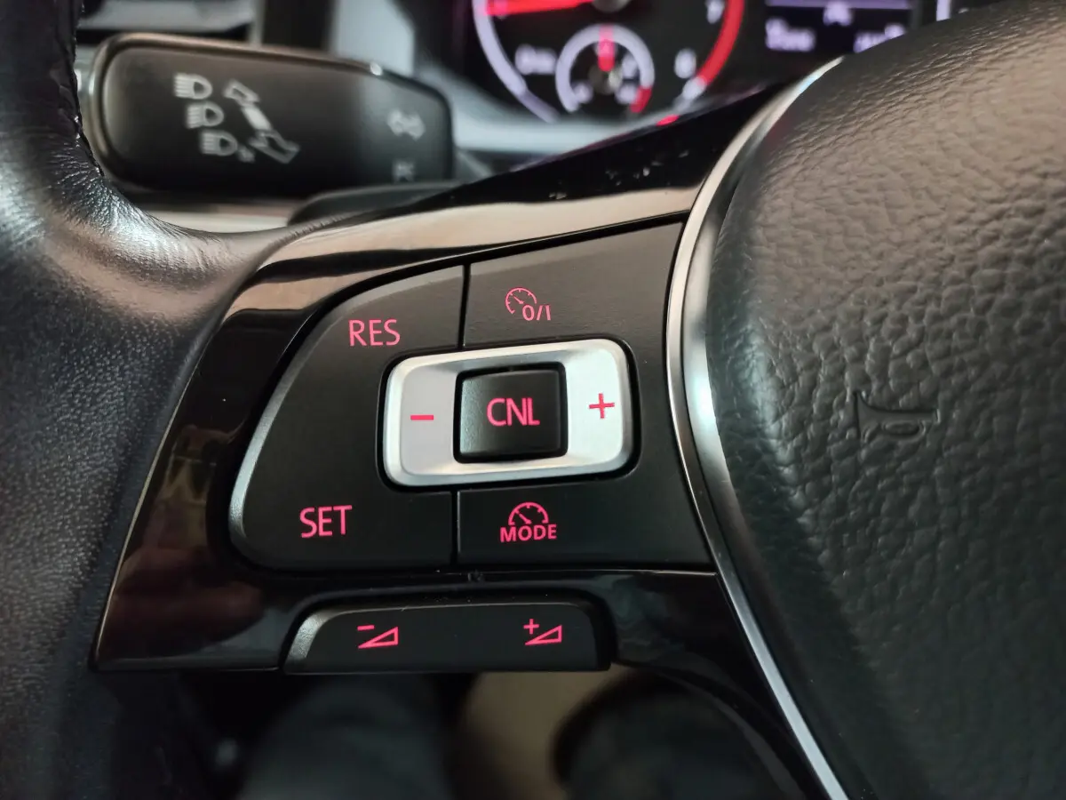 Gros plan sur les commandes du régulateur de vitesse du volant cuir noir d'une Volkswagen Polo 2020.