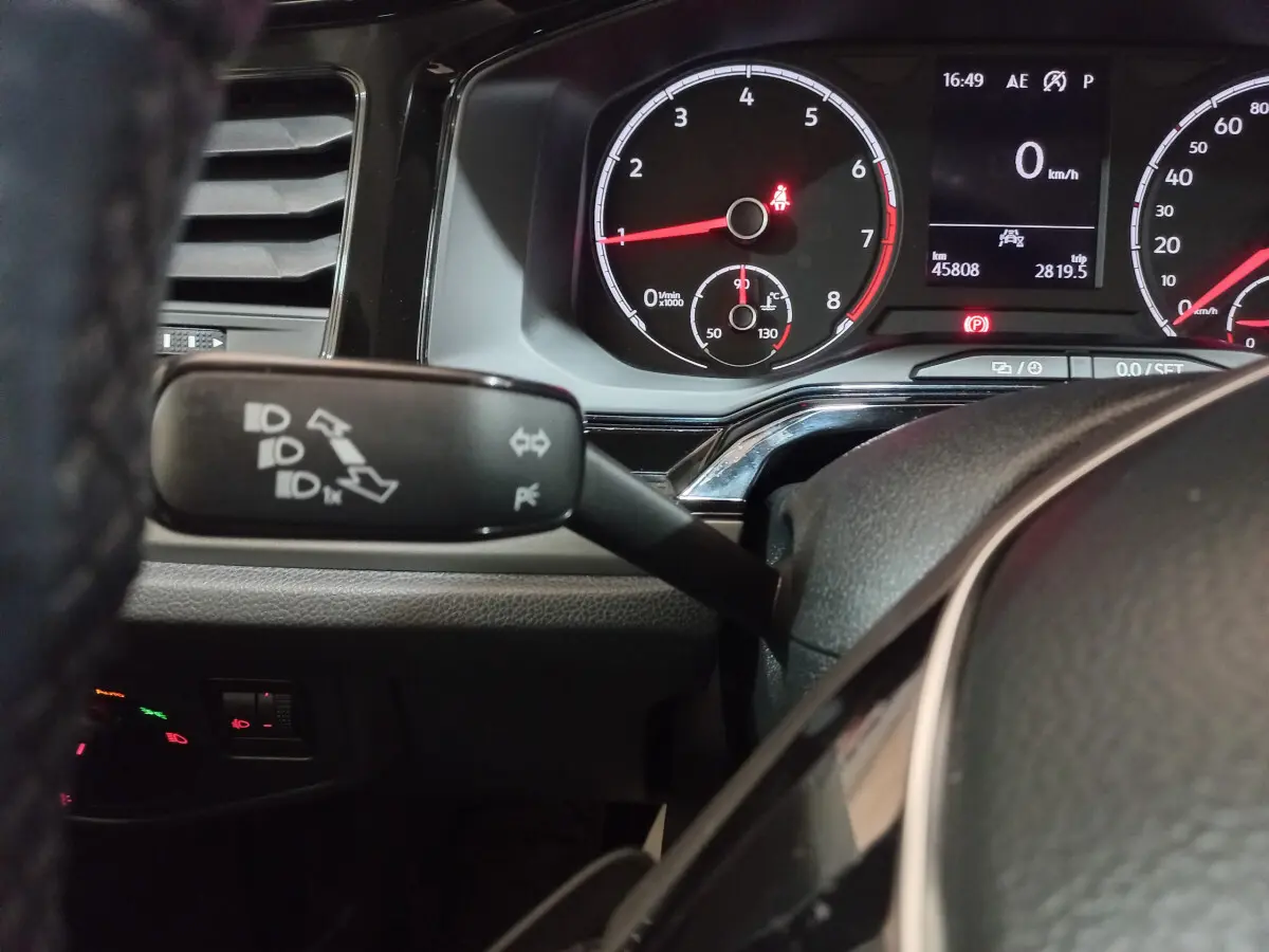 Gros plan sur le tableau de bord et le commodo gauche de la Volkswagen Polo noire, affichage digital et compte-tours visibles.