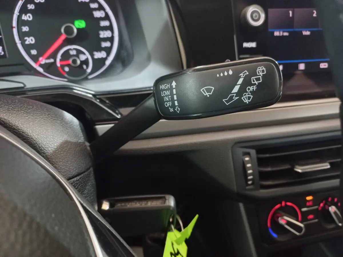 Gros plan sur la commande d’essuie-glace à gauche du volant dans l’habitacle noir d’une Volkswagen Polo 2020.