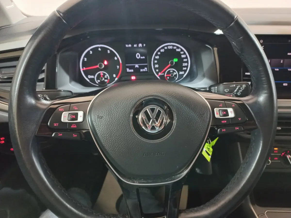 Vue rapprochée du volant en cuir noir d'une Volkswagen Polo 2020 avec tableau de bord numérique et commandes intégrées.