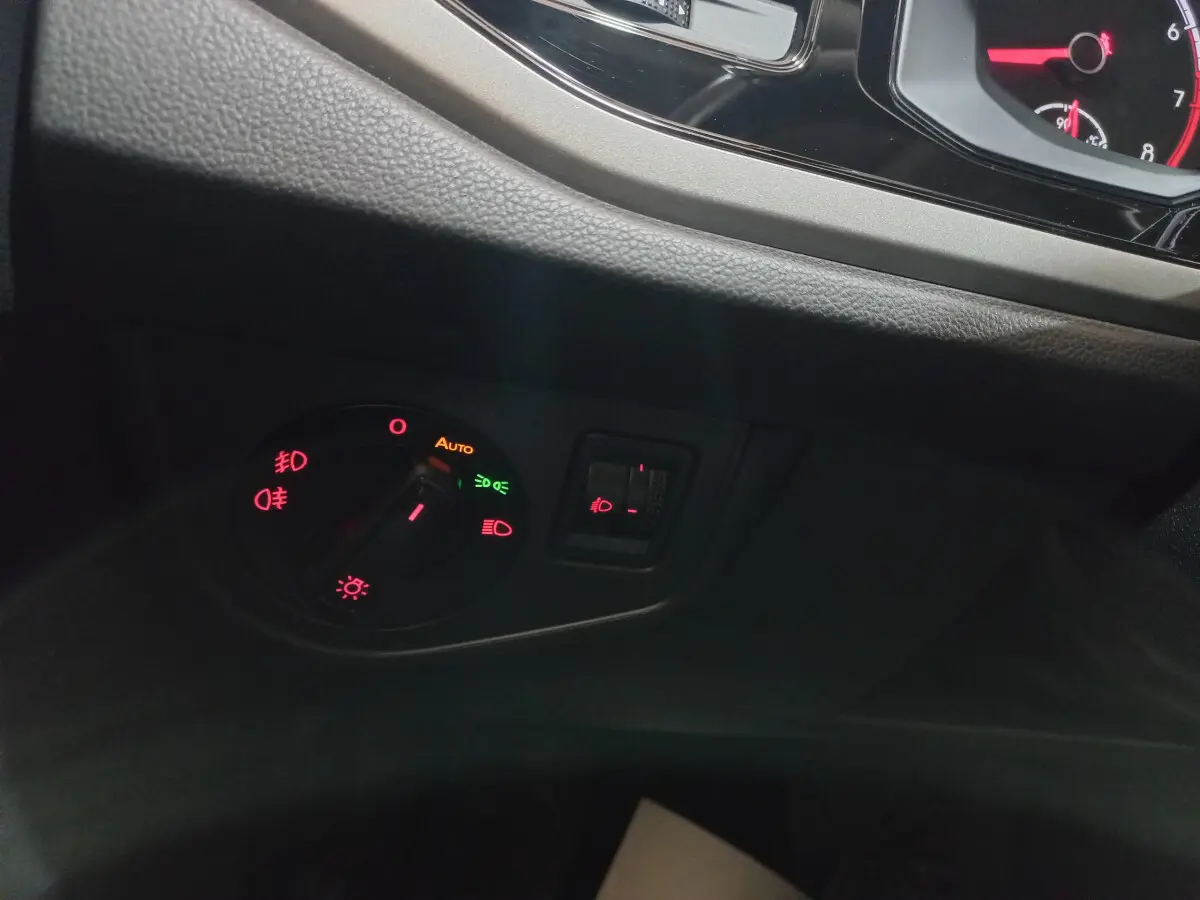 Gros plan sur le bouton de commande des phares et réglage des feux antibrouillard dans l'habitacle d'une Volkswagen Polo noire 2020.
