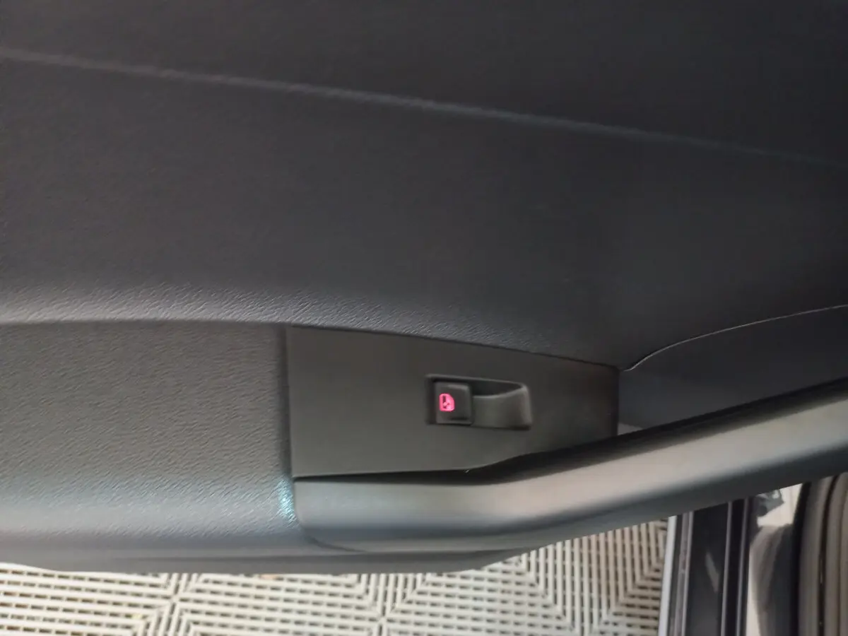 Bouton de verrouillage des portes rouge sur la garniture intérieure noire de la porte avant droite d'une Volkswagen Polo noire.