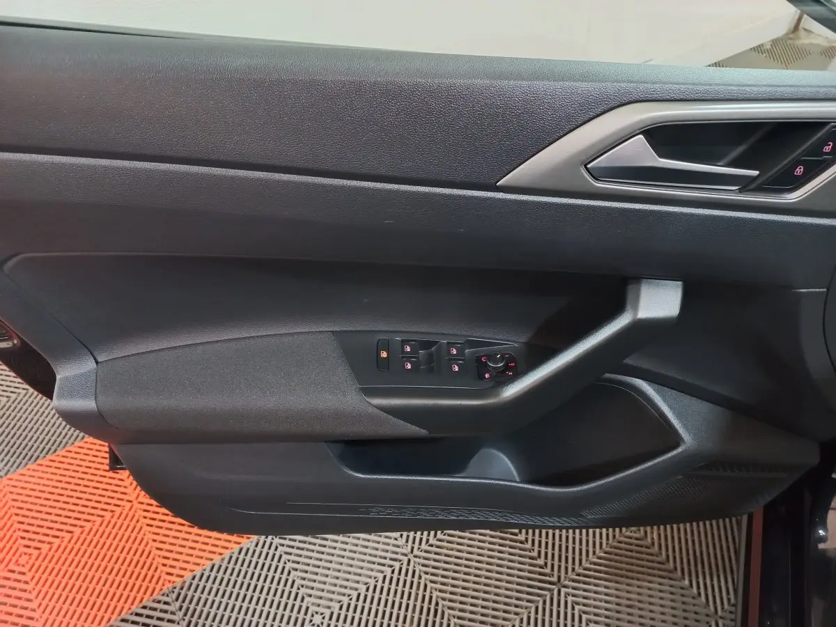 Vue rapprochée de la porte côté gauche noire de la Volkswagen Polo 2020 avec commandes électriques des vitres et serrure intégrée.