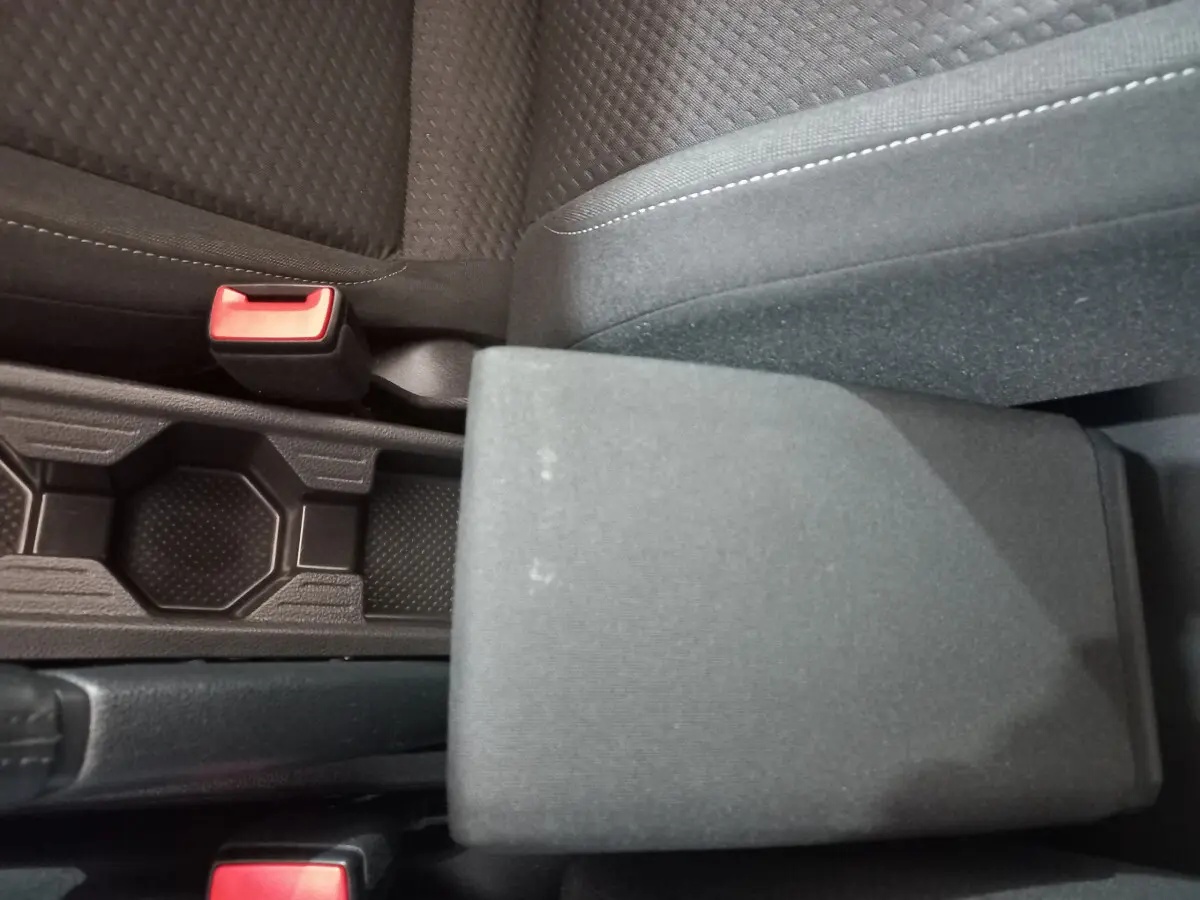 Gros plan sur l'accoudoir central et les sièges noirs en tissu de la Volkswagen Polo 2020 côté conducteur.