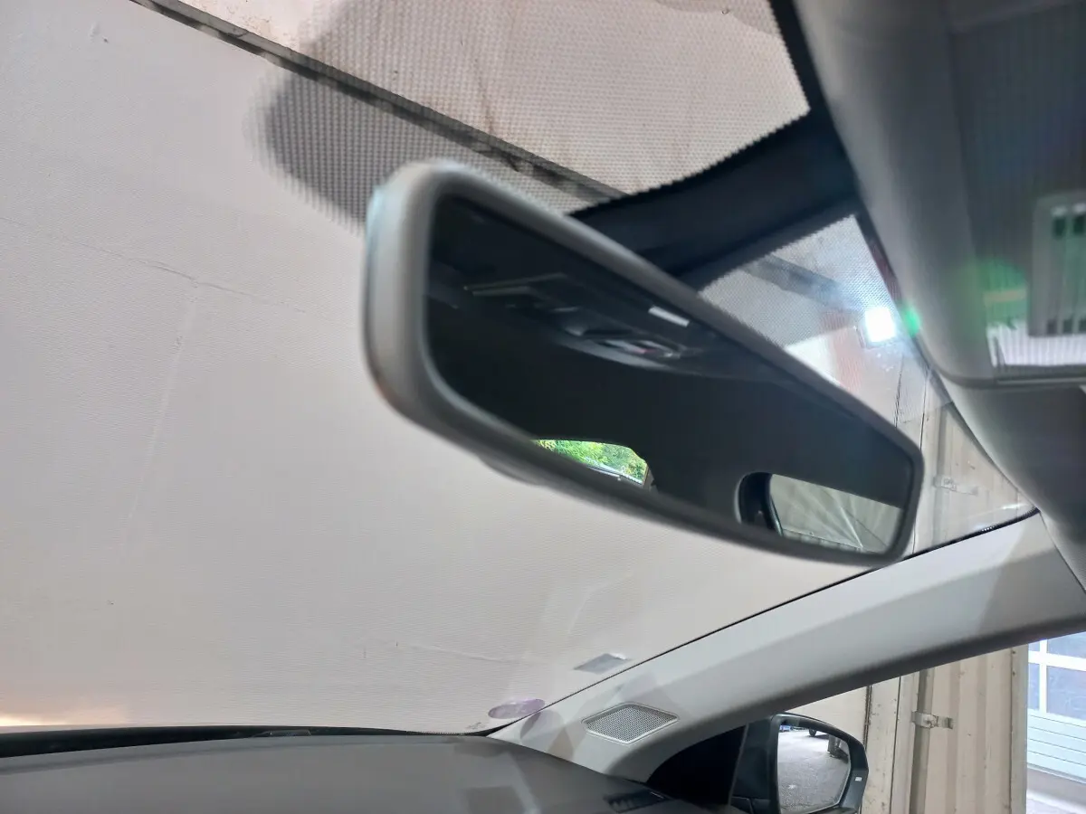 Vue intérieure du rétroviseur central d'une Volkswagen Polo noire 2020, avec partie du pare-brise et montant de porte visible.