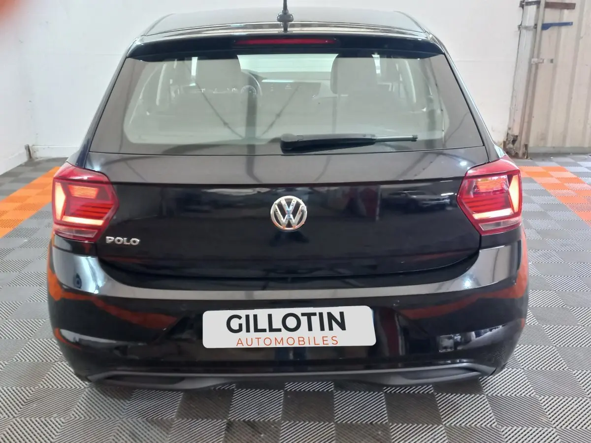 Vue arrière d'une Volkswagen Polo noire de 2020 avec feux arrière allumés dans un garage.