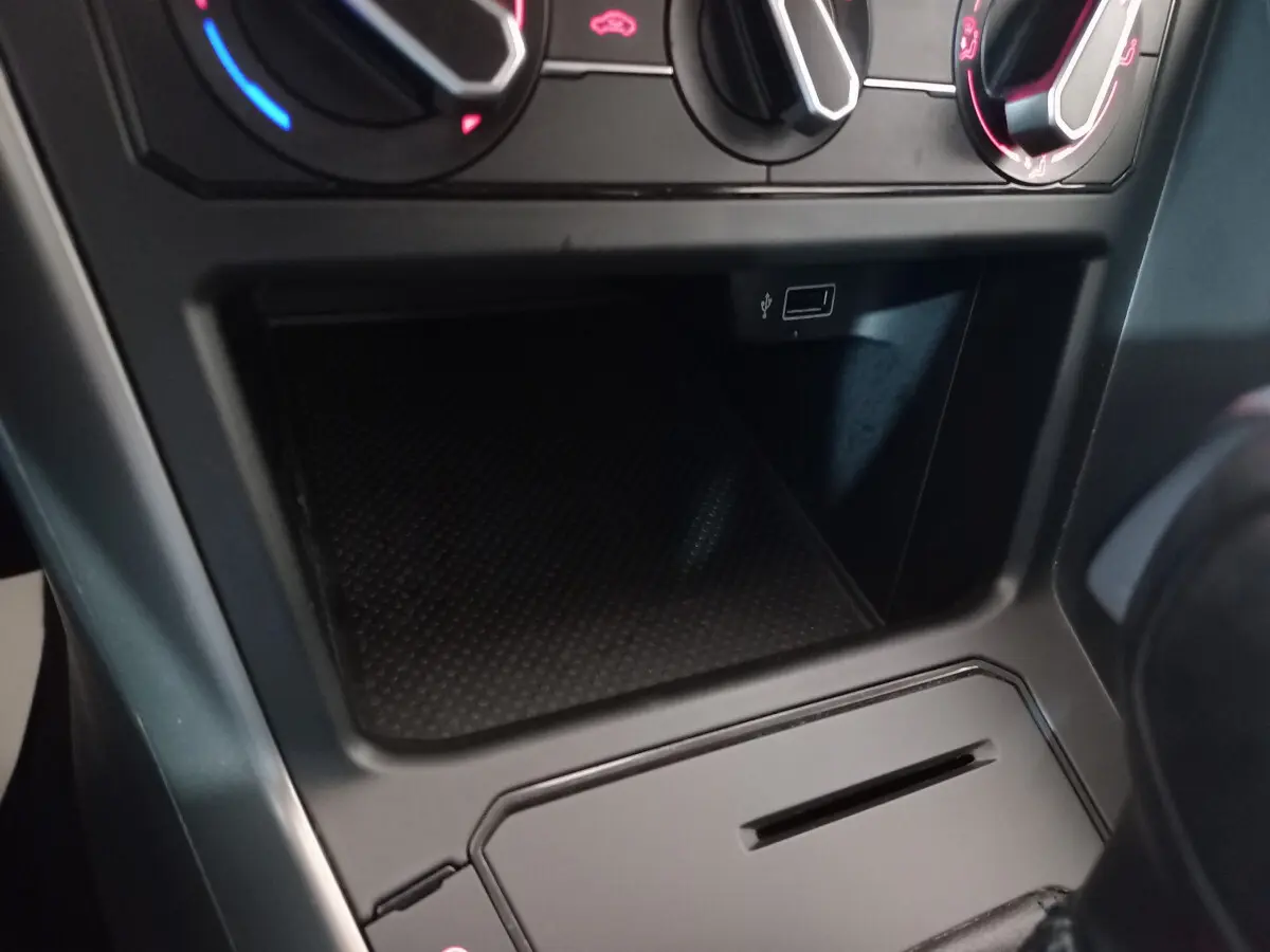Gros plan sur la console centrale noire de la Volkswagen Polo 2020, montrant les commandes de climatisation et une prise USB.