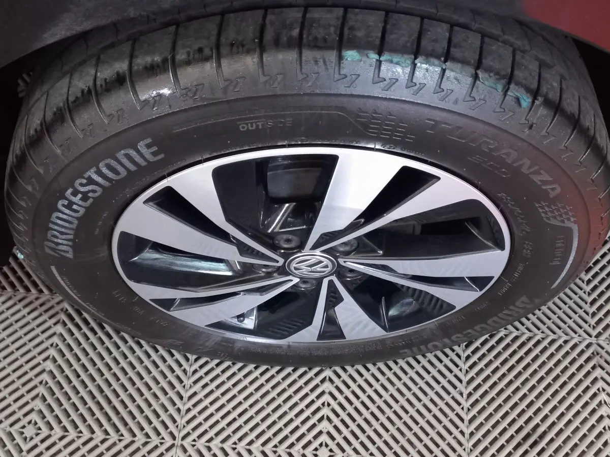 Gros plan sur la roue avant gauche d'une Volkswagen Polo noire avec jante alliage bicolore et pneu Bridgestone Turanza.
