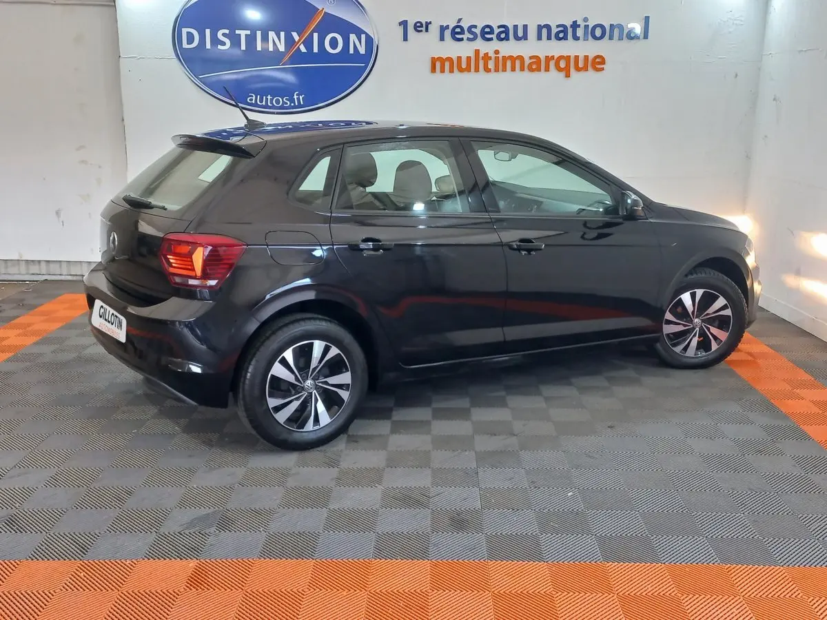 Volkswagen Polo noire vue de profil côté gauche dans un showroom avec jantes alliage et feux arrière allumés.